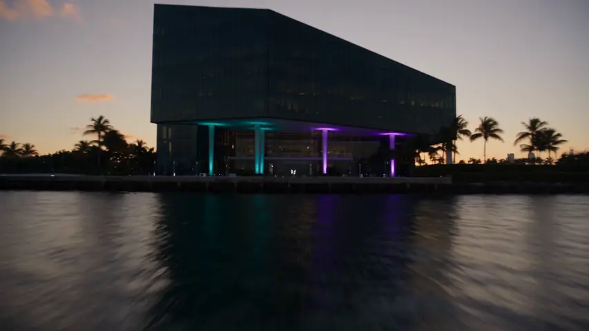 An angular waterfront stage building lights up at dusk before the camera moves inside to camera rigs facing a wall carrying the Unreal mark