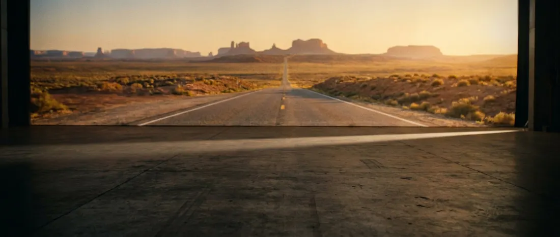 An empty soundstage, its doors open onto a desert highway at dusk